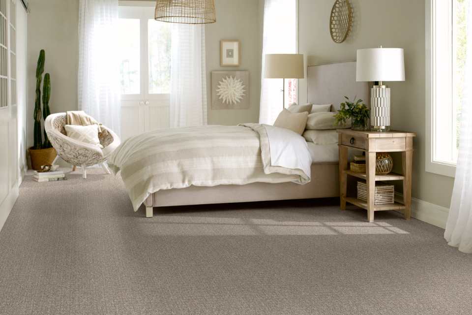 patterned grey carpet in monochromatic neutral bedroom with rattan lighting and artwork